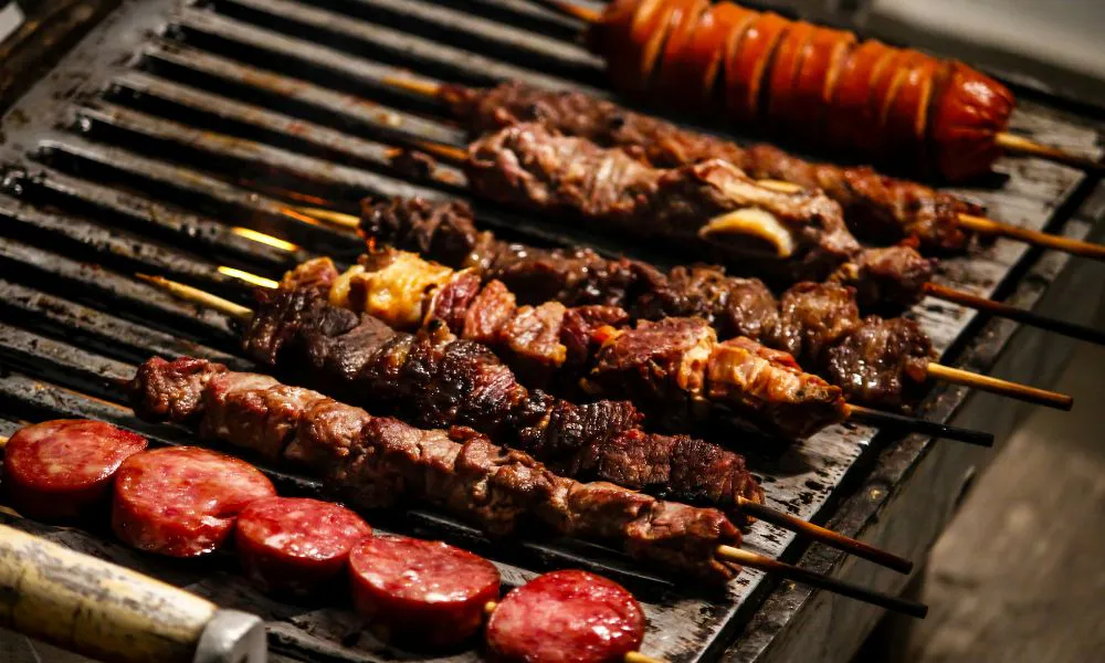 Grilled skewers of meat and sausage cooking on a grill at Hot Point The Dalles, a Chinese restaurant in The Dalles